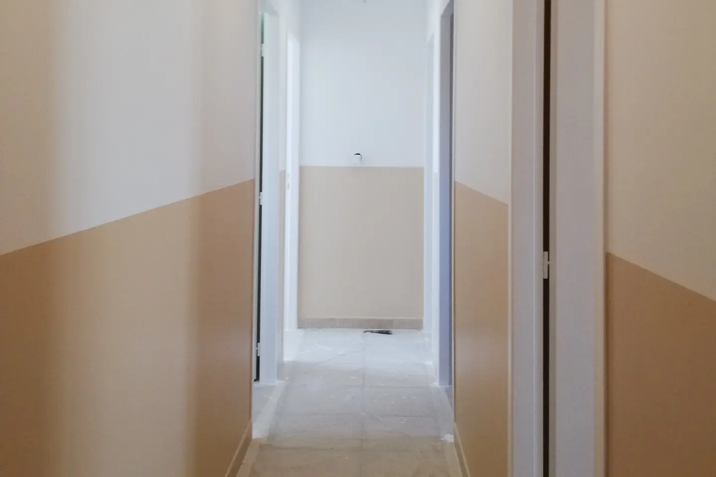 Couloir d'appartement repeint en blanc et beige, sol encore protégé, par un artisan peintre de Toulon